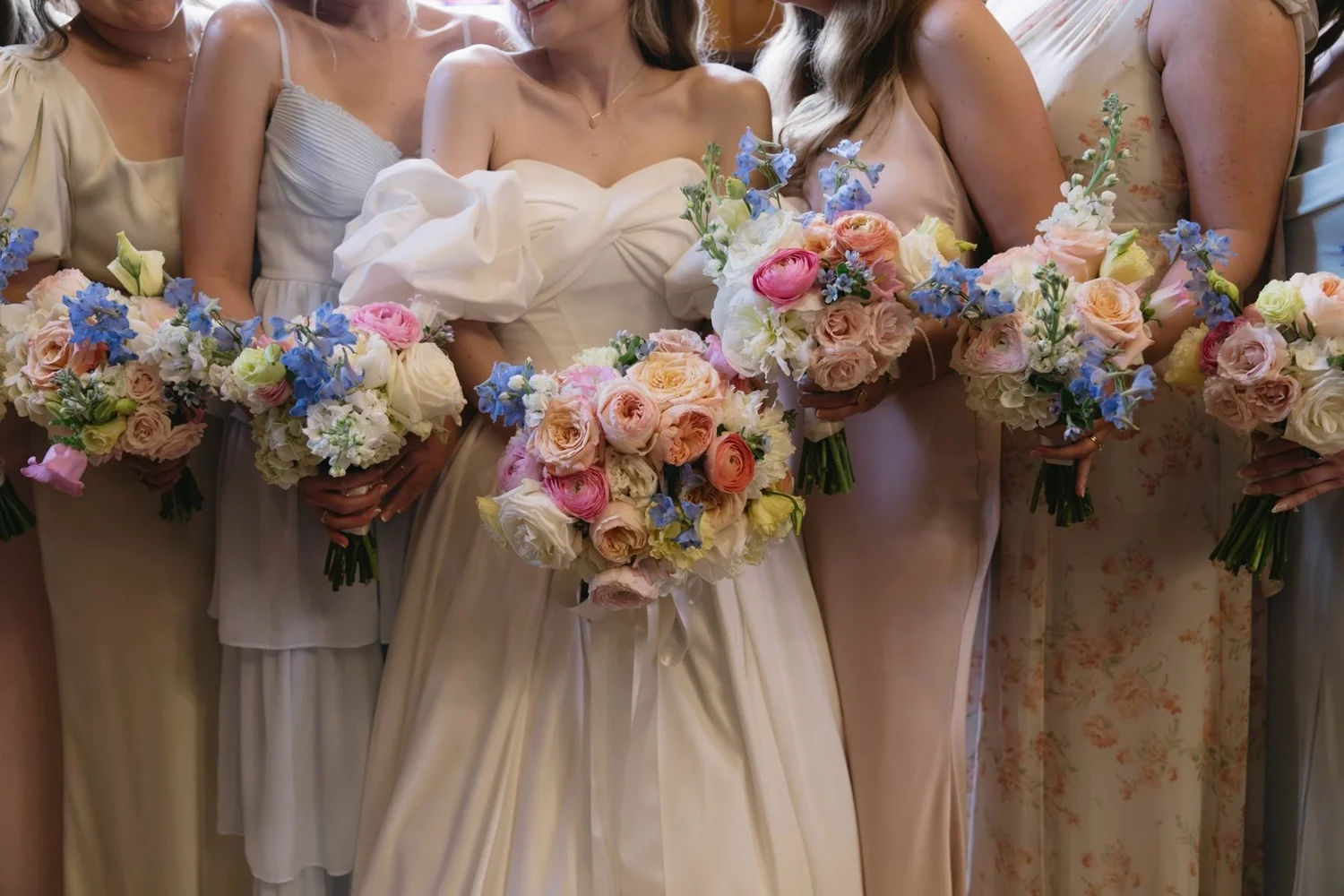 Bridal and bridesmaid bouquets of garden roses, ranunculus, stock and delphinium held in a row