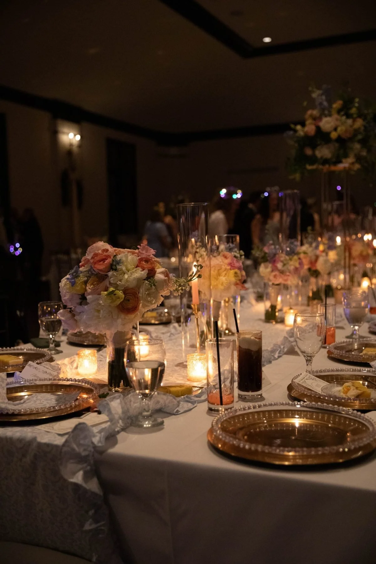 Candlelit table glowing with bud bouquets after dark