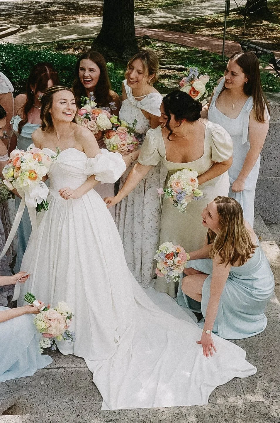 Bridal party gathered around the bride on stone steps, shot on film