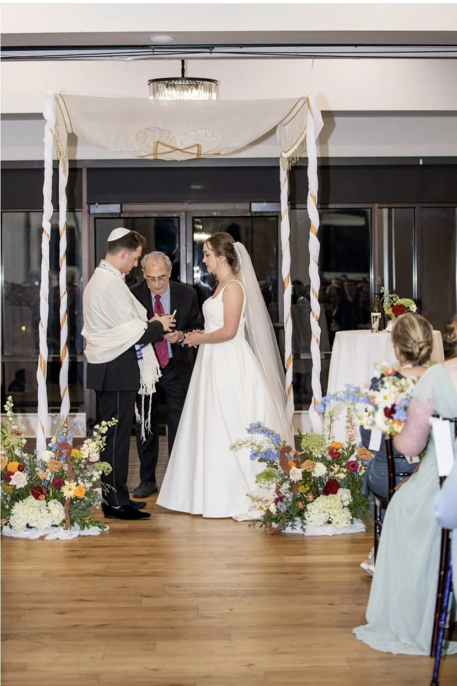 Draped chuppah with floor-level floral meadows at each post