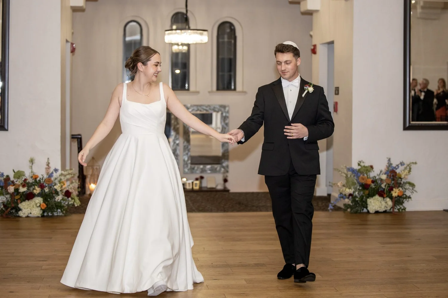Couple making their grand entrance between floral arrangements