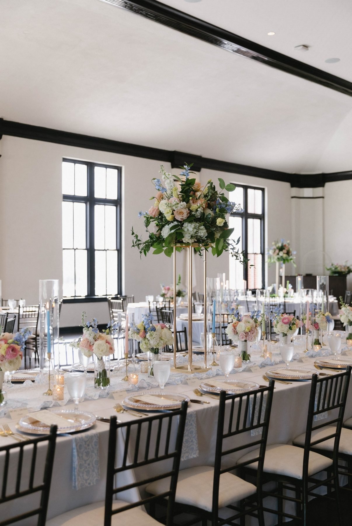 Long table with a tall gilded centerpiece, bud bouquets and pastel tapers