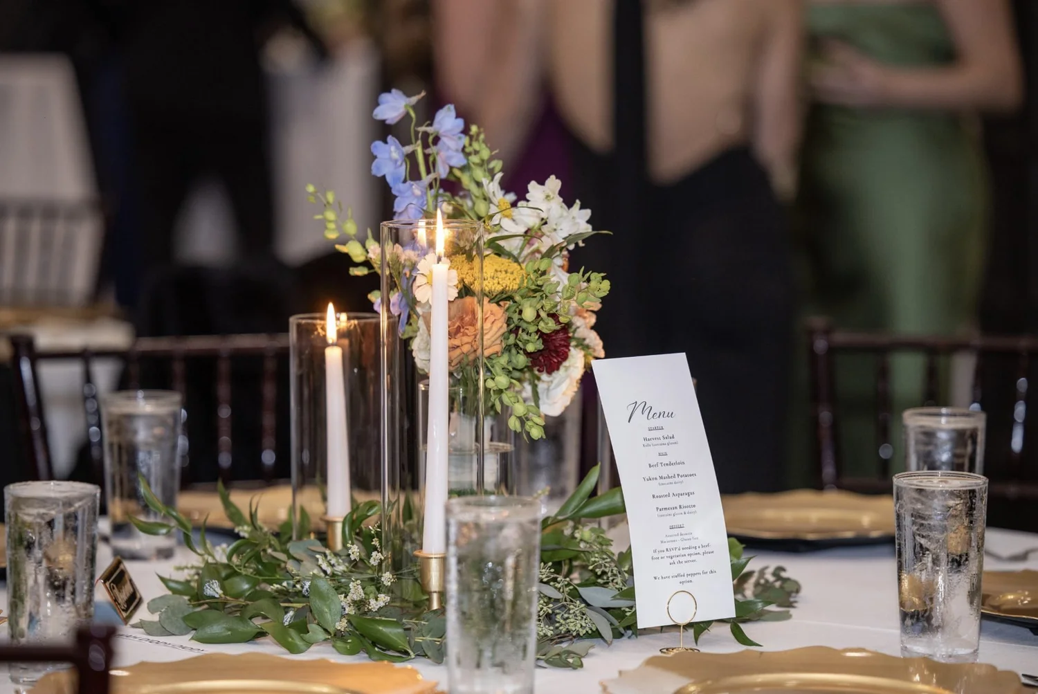 Candlelit reception table with greenery garland and printed menu
