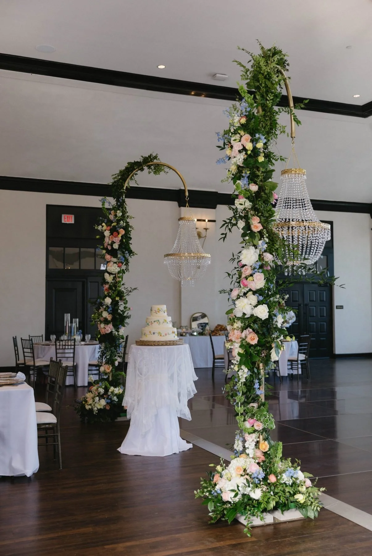 Two flower-wrapped brass hoops suspending crystal chandeliers