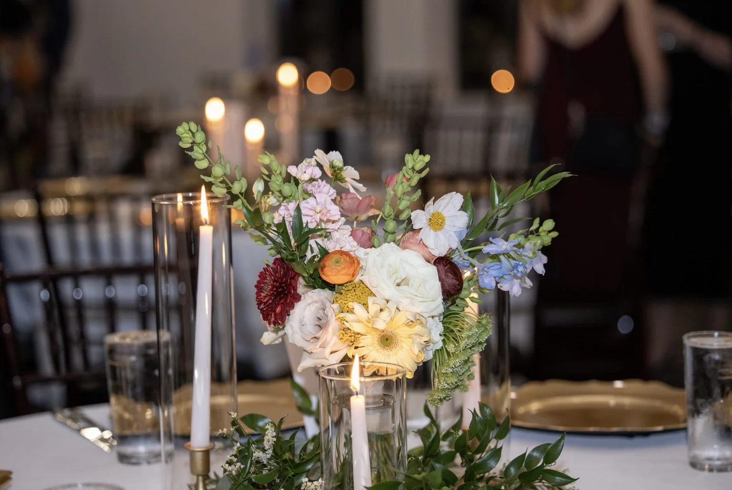 Garden centerpiece with taper candles in glass hurricanes
