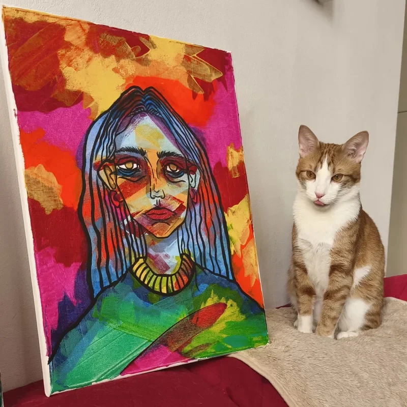Psycho, il gatto rosso di Fiorella, seduto accanto a un suo quadro