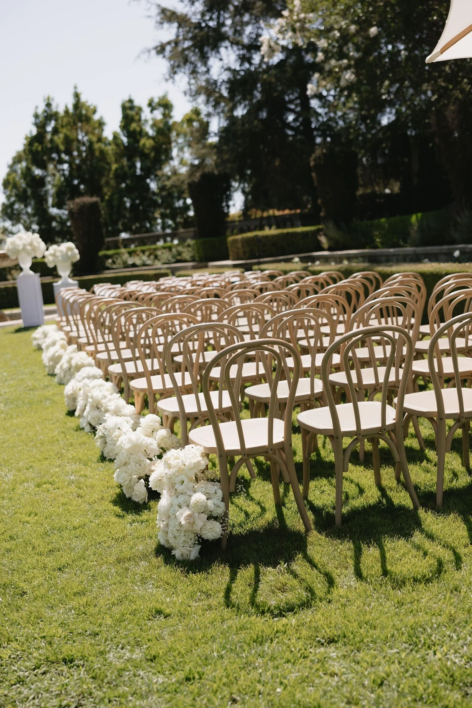 Ceremony chairs and white floral arrangements in a garden