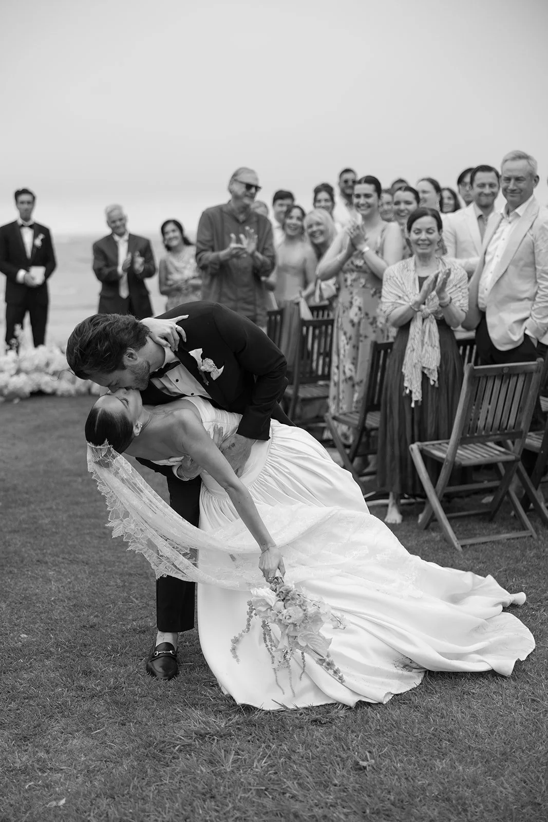 Newlyweds kissing as guests look on