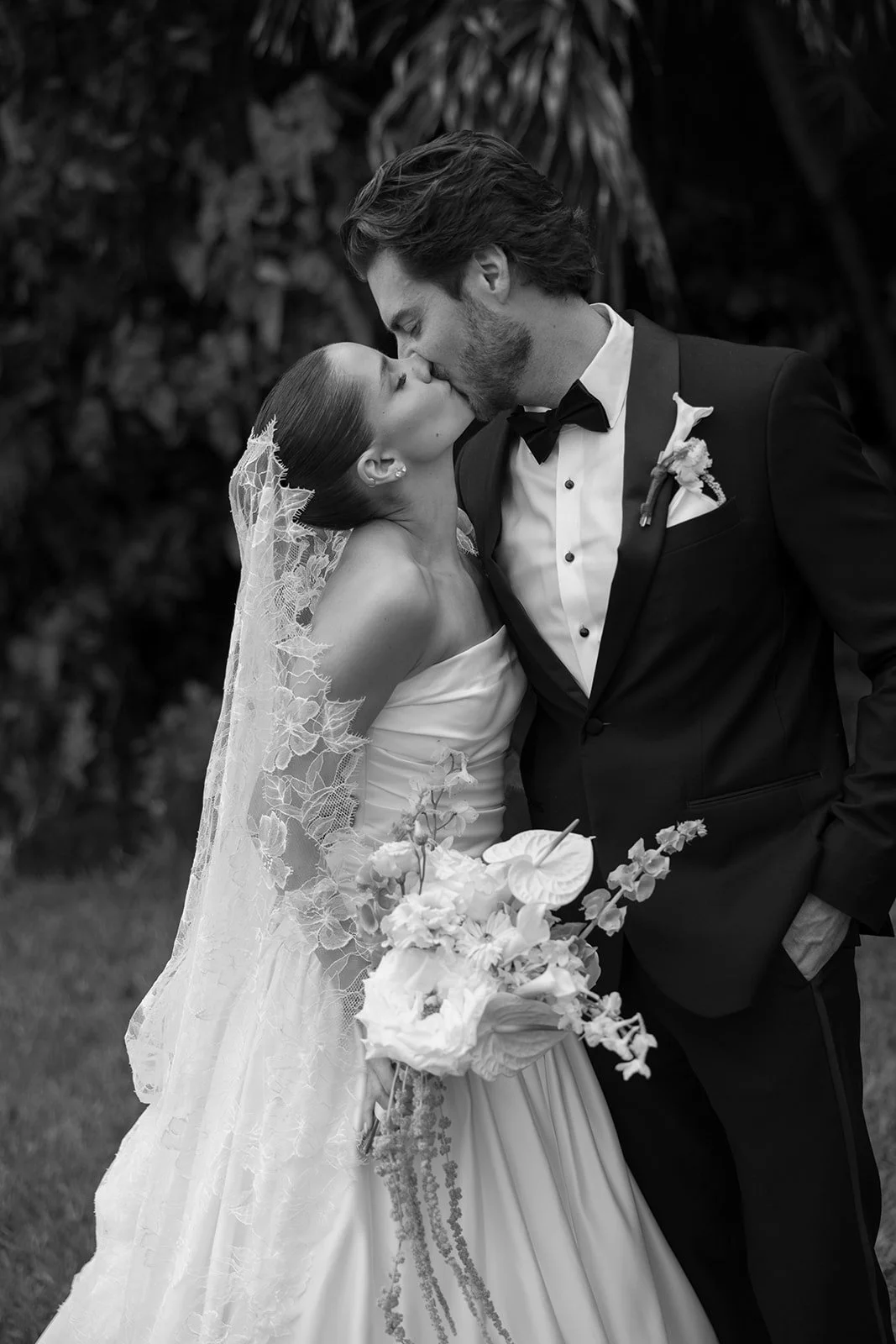 Black-and-white portrait of newlyweds with a white bouquet