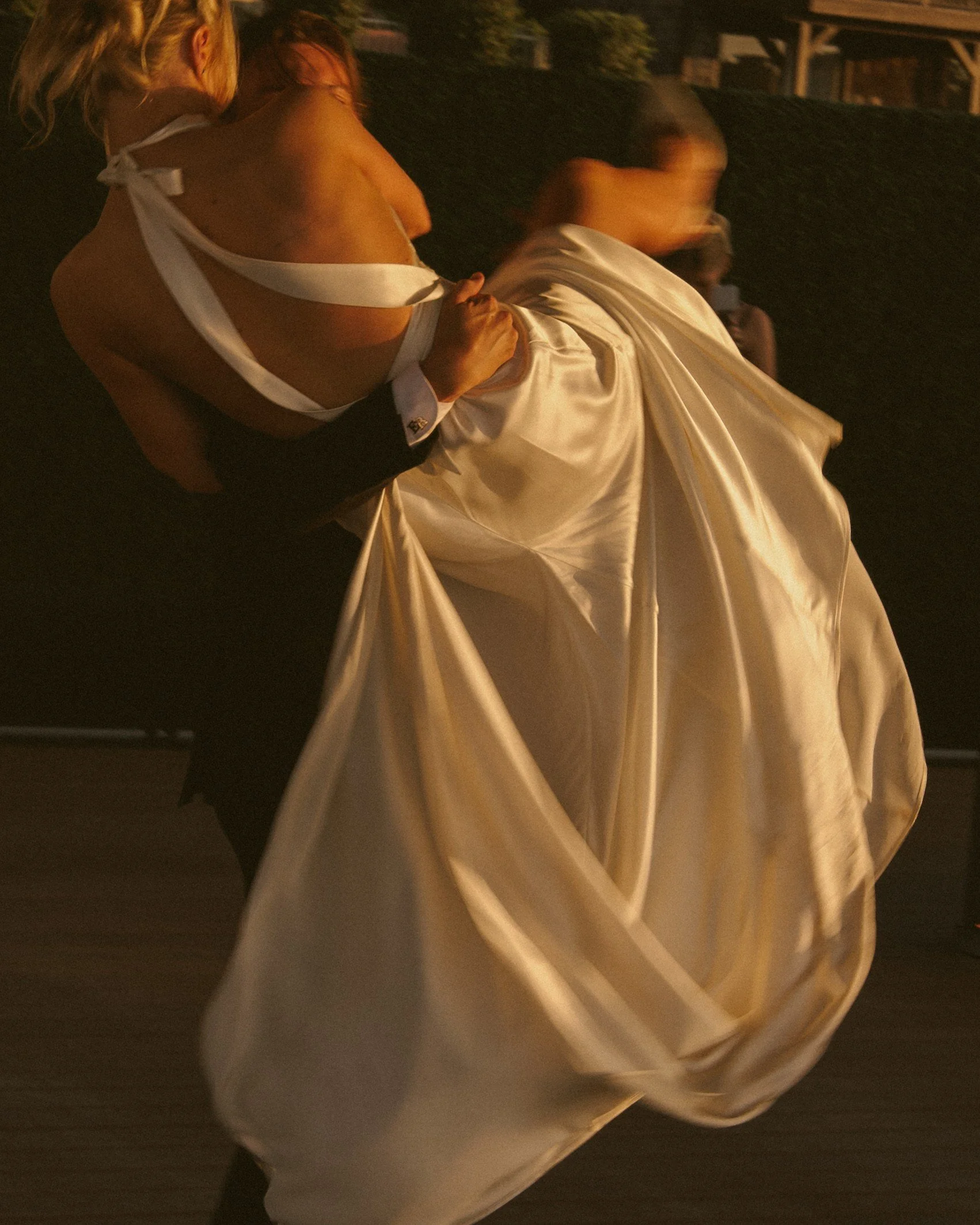 Bride gathering her satin dress in warm evening light