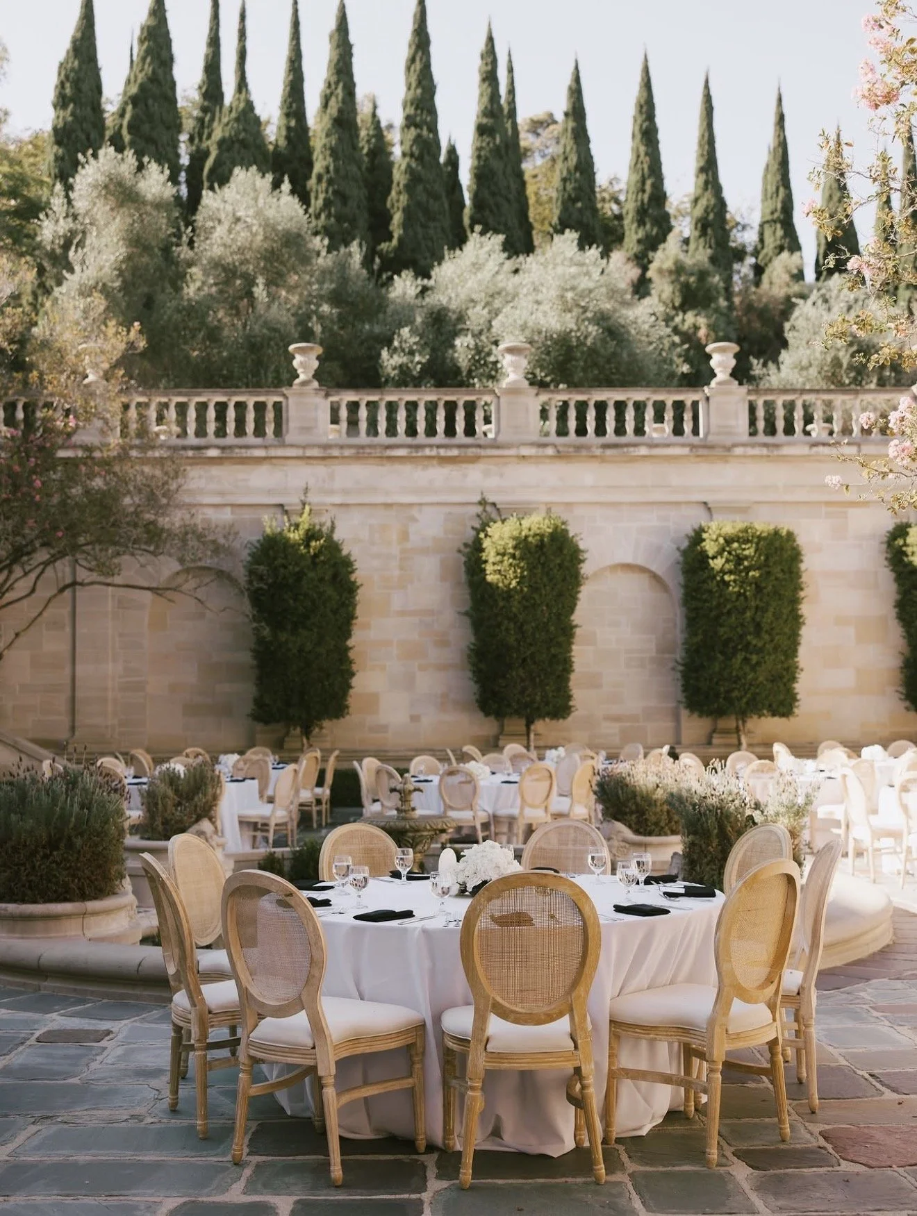 Outdoor wedding reception with white linens and cypress trees