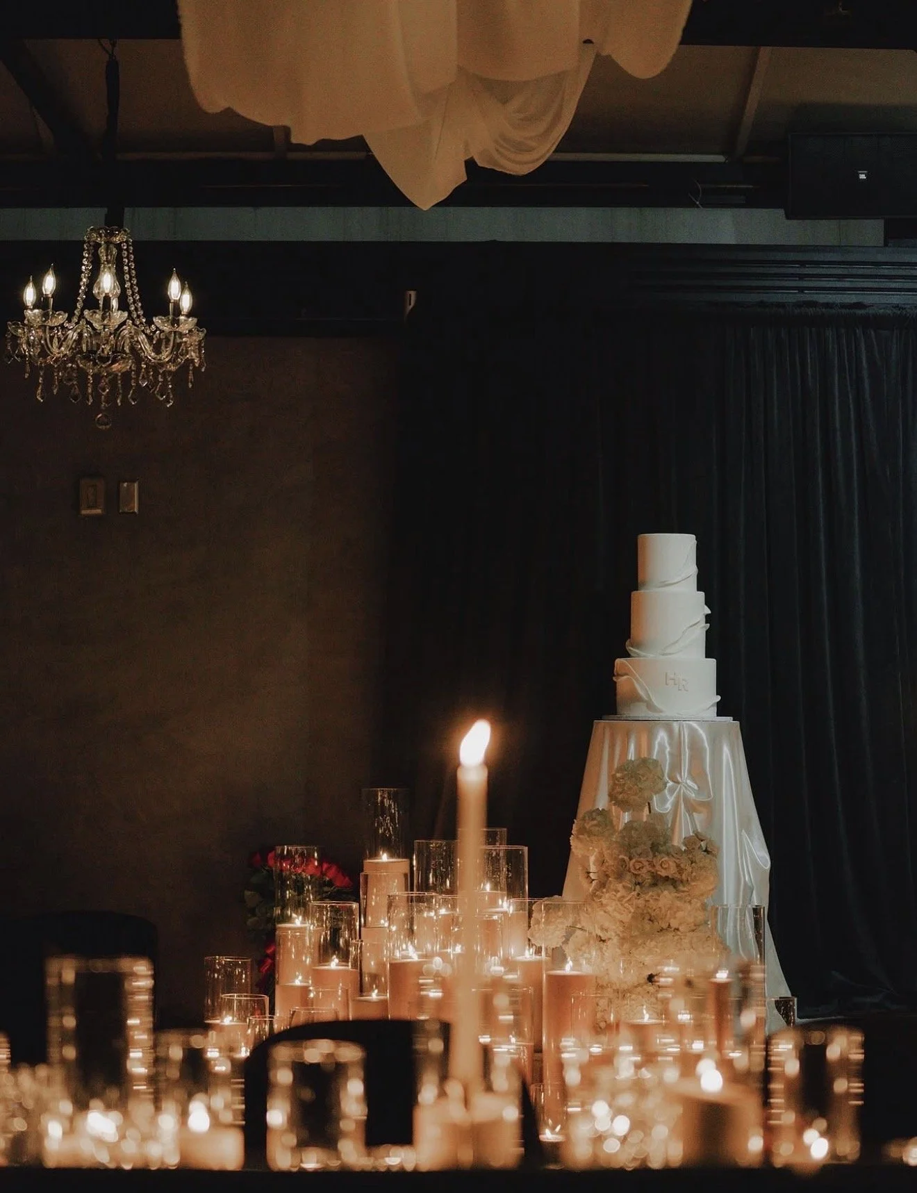 Candlelit reception with a tiered wedding cake and draping