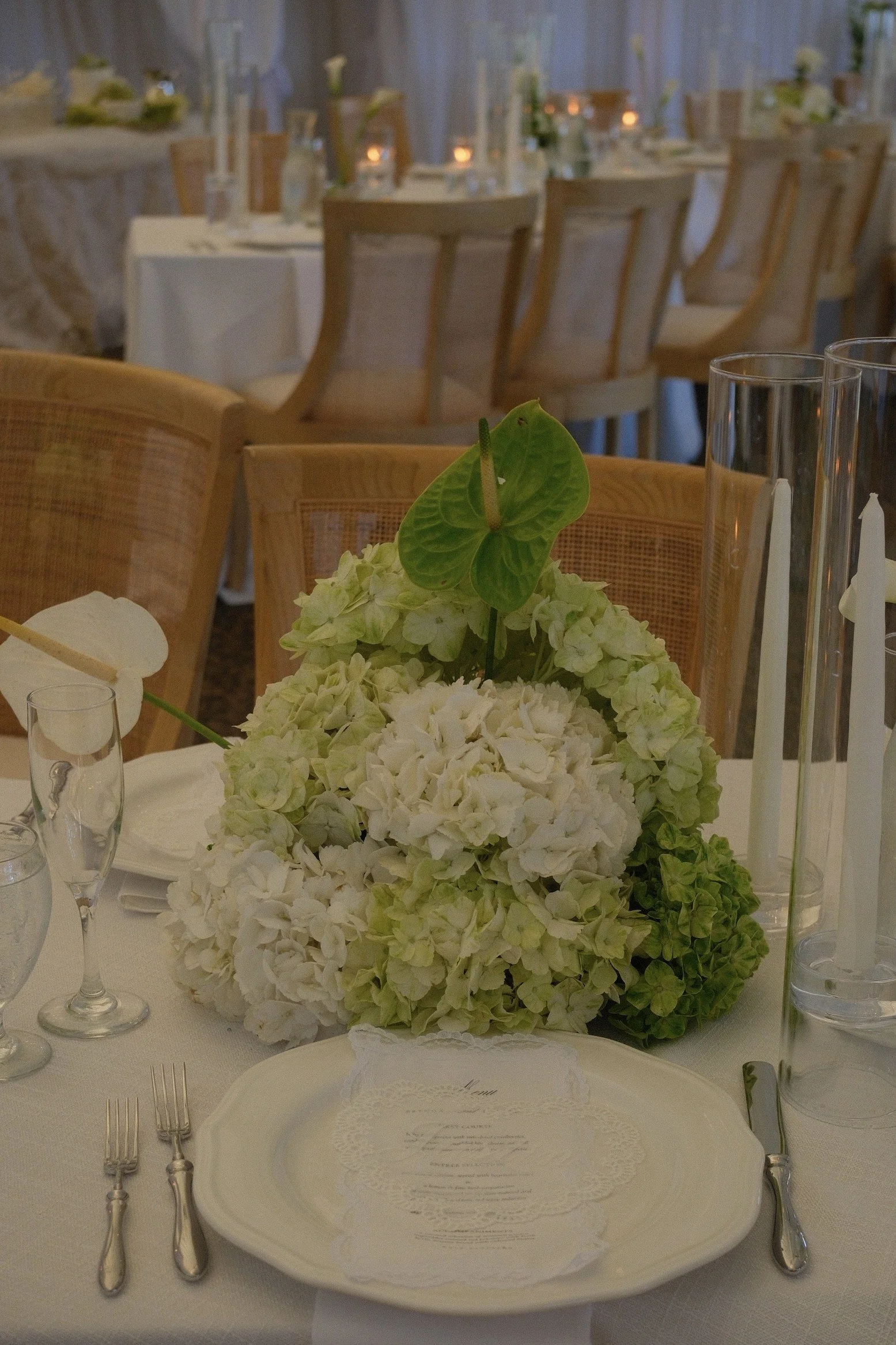 White and green centerpiece beside a place setting