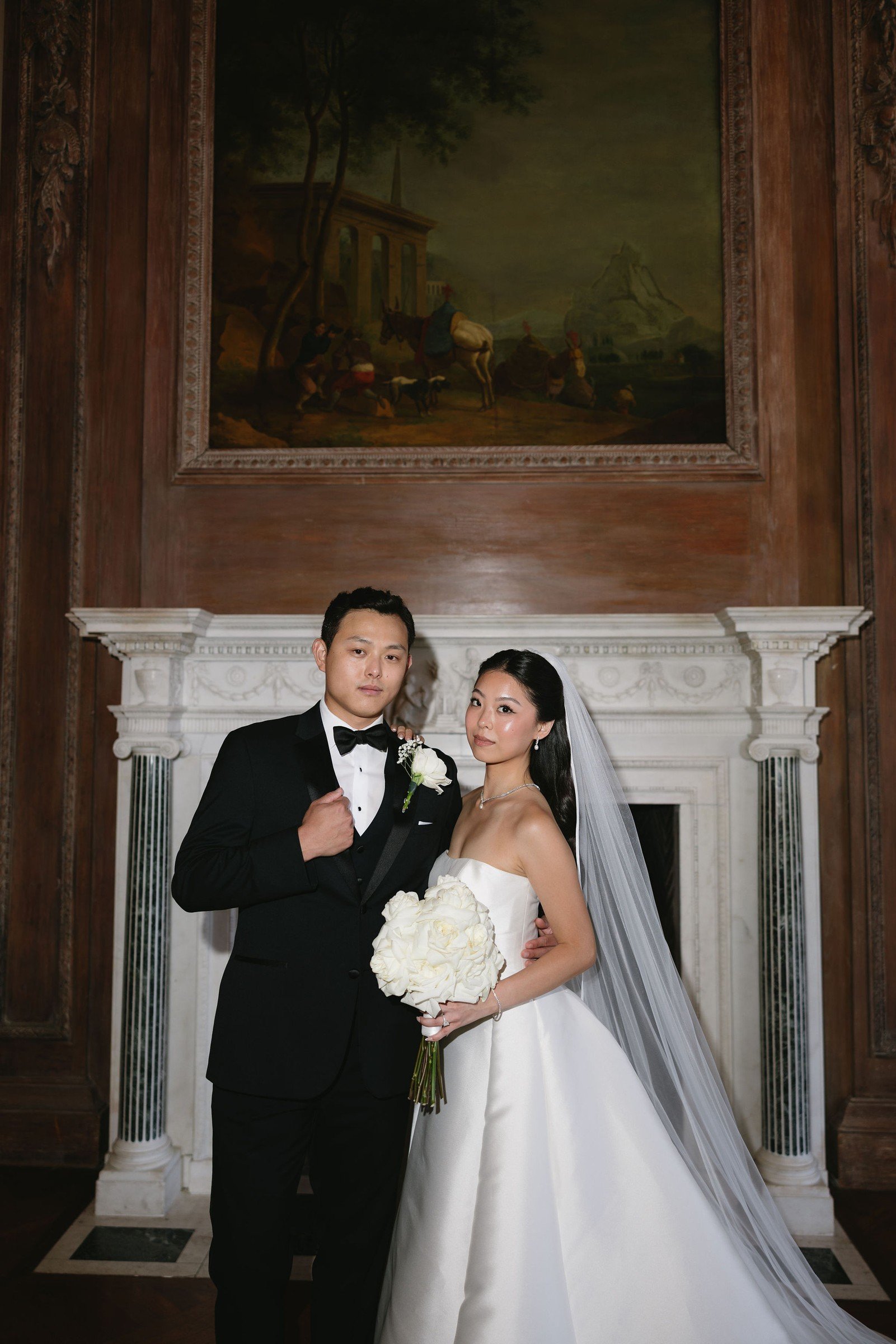 Newlyweds beside an ornate fireplace