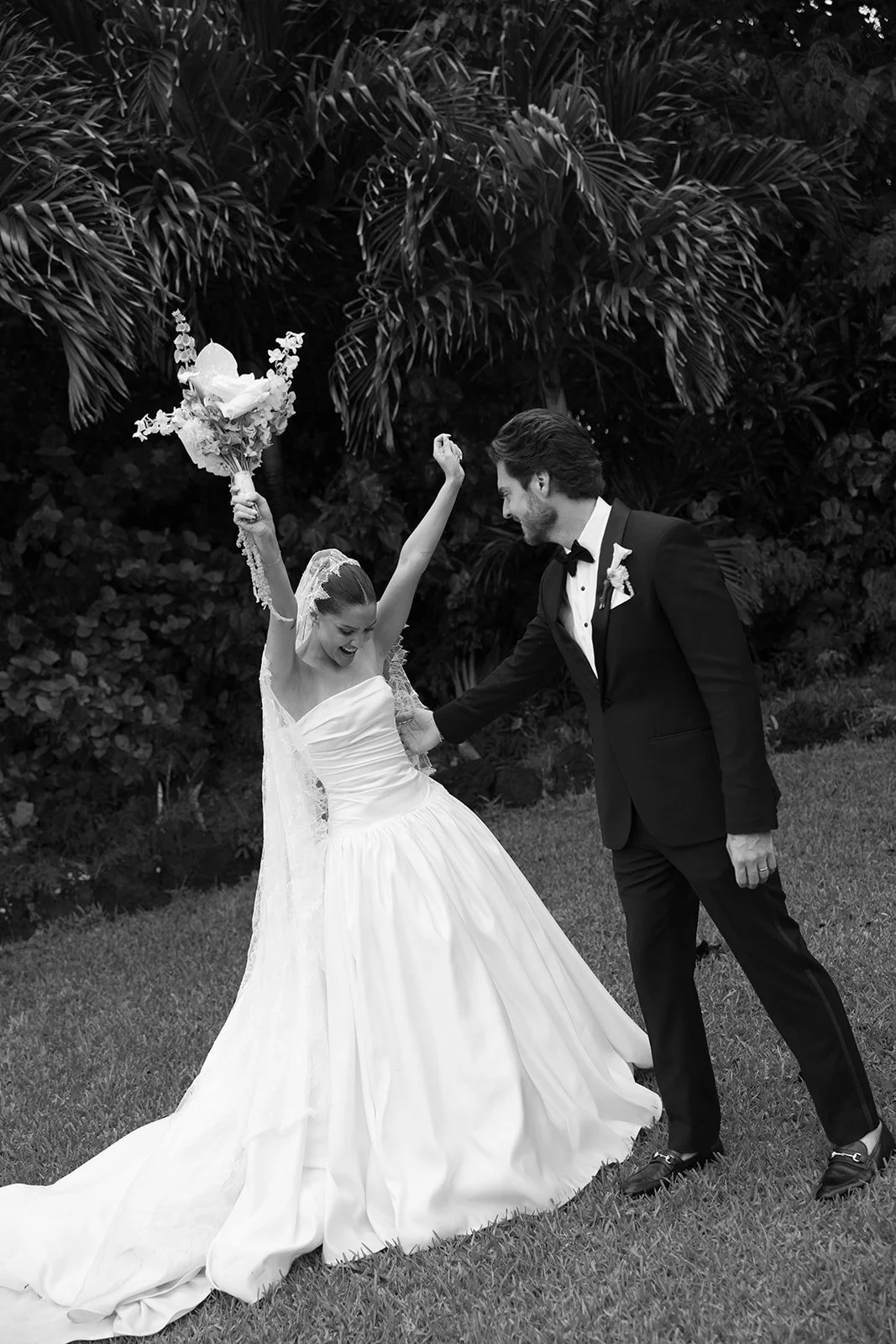 Newlyweds celebrating with a raised bouquet
