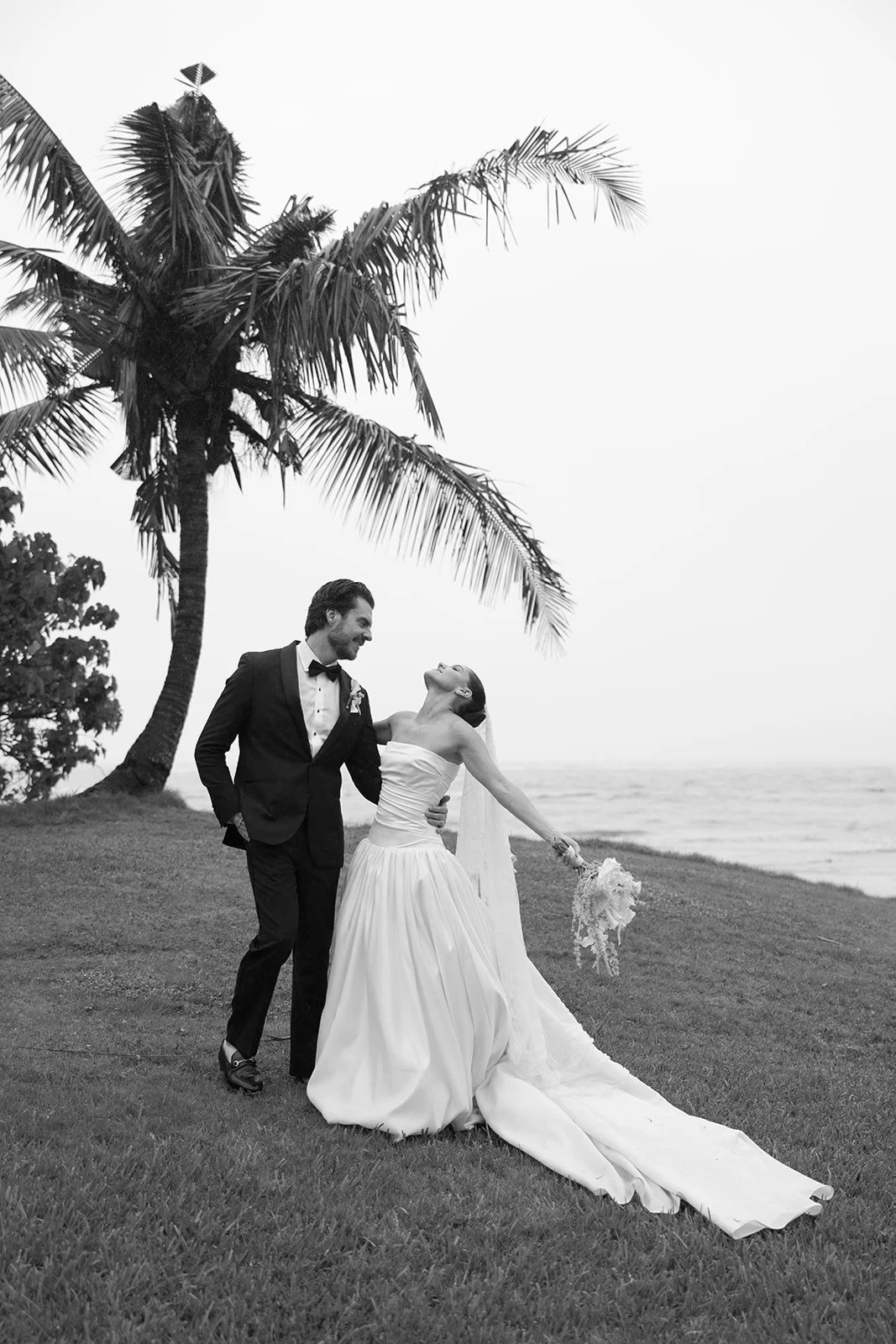 Newlyweds beneath palm trees beside the ocean
