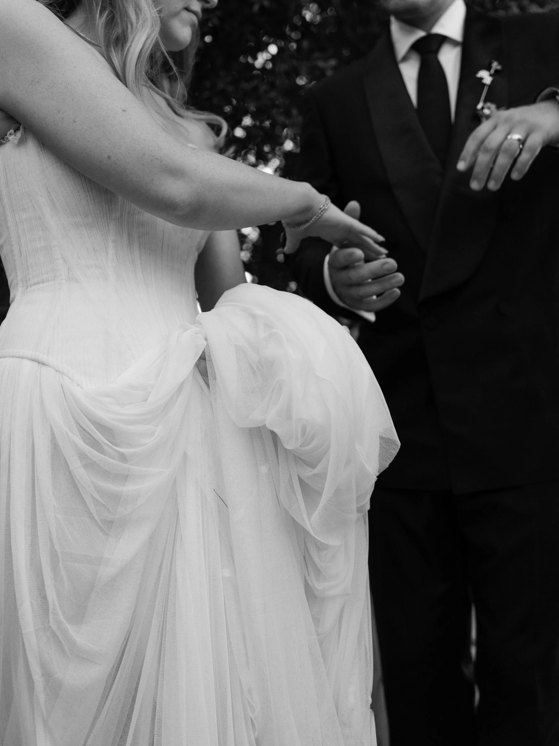 Black-and-white close-up of newlyweds holding hands