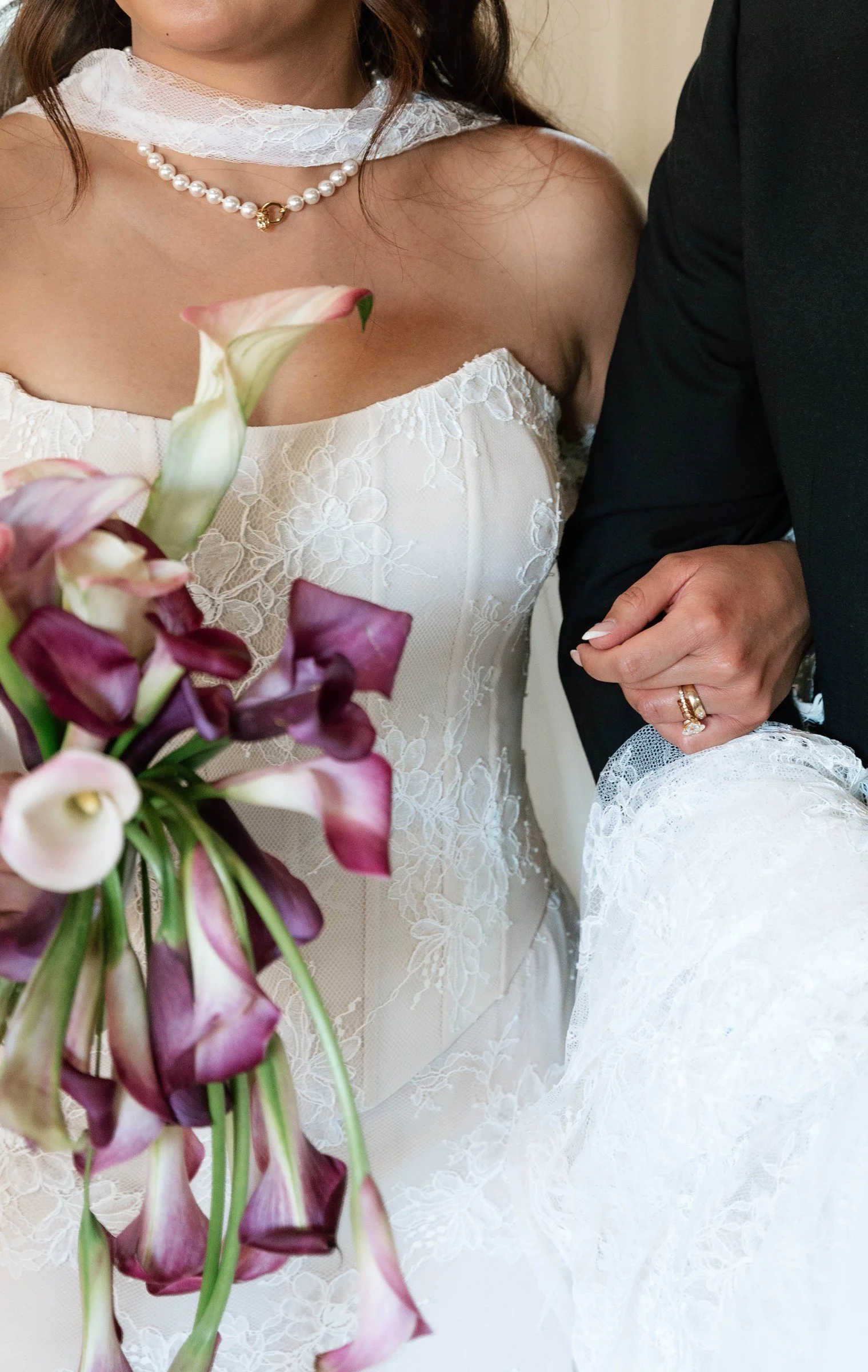 Wedding bouquet beside a pearl necklace and white dress