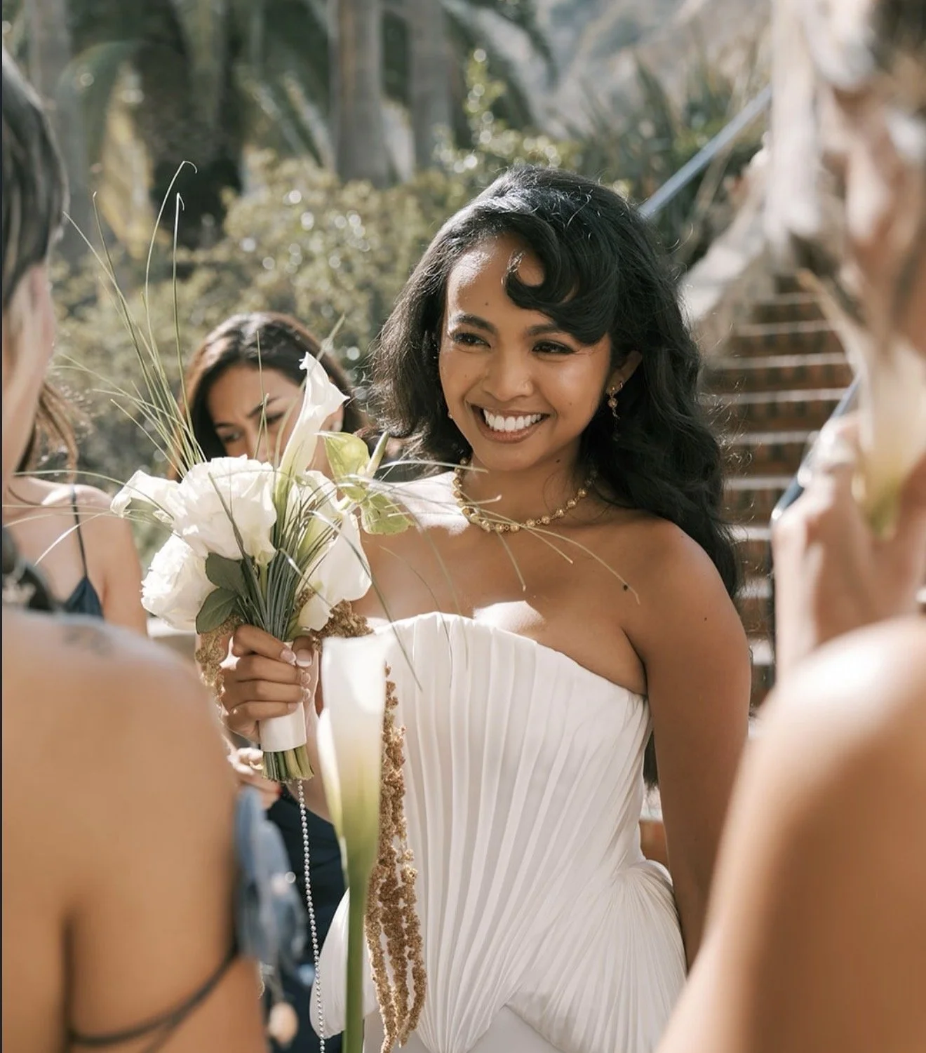 Bride holding a sculptural white bouquet with trailing greenery