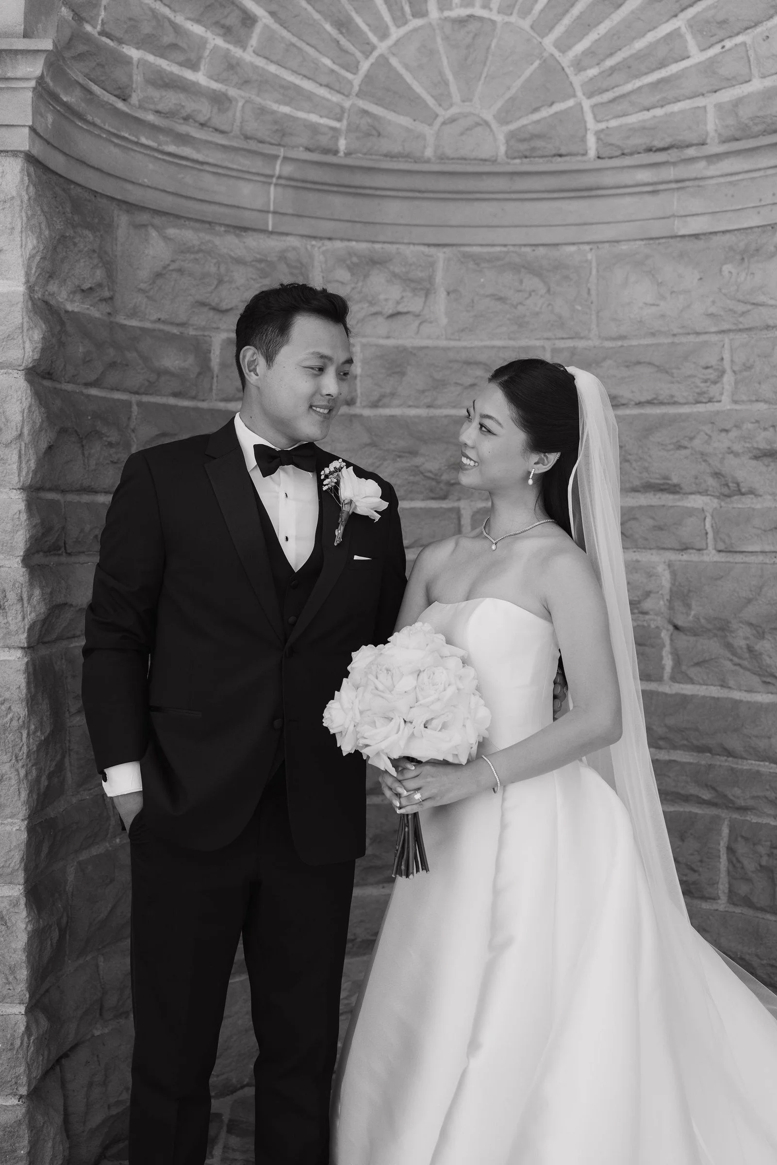 Black-and-white portrait of newlyweds in a stone doorway
