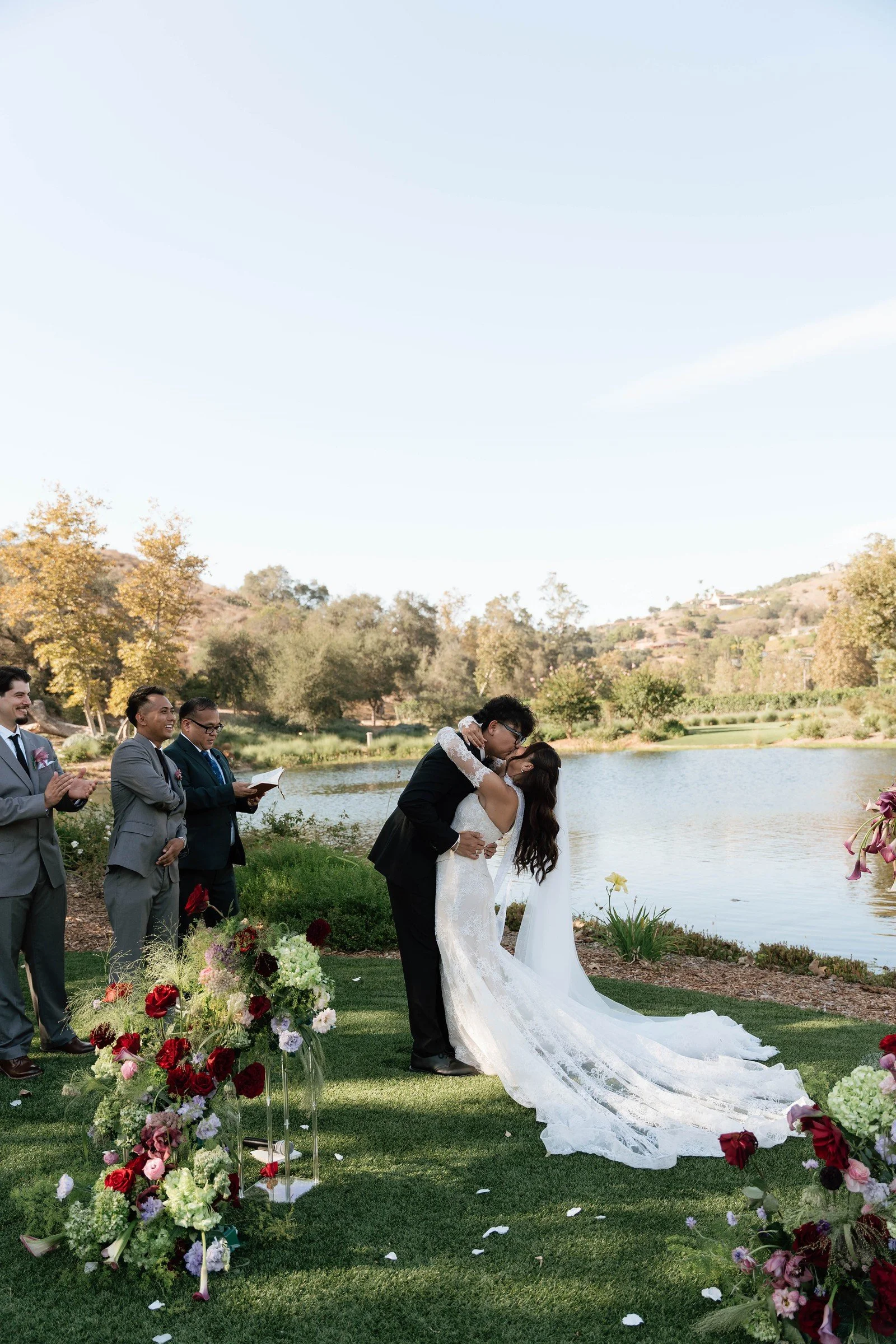 Newlyweds kissing at a lakeside ceremony