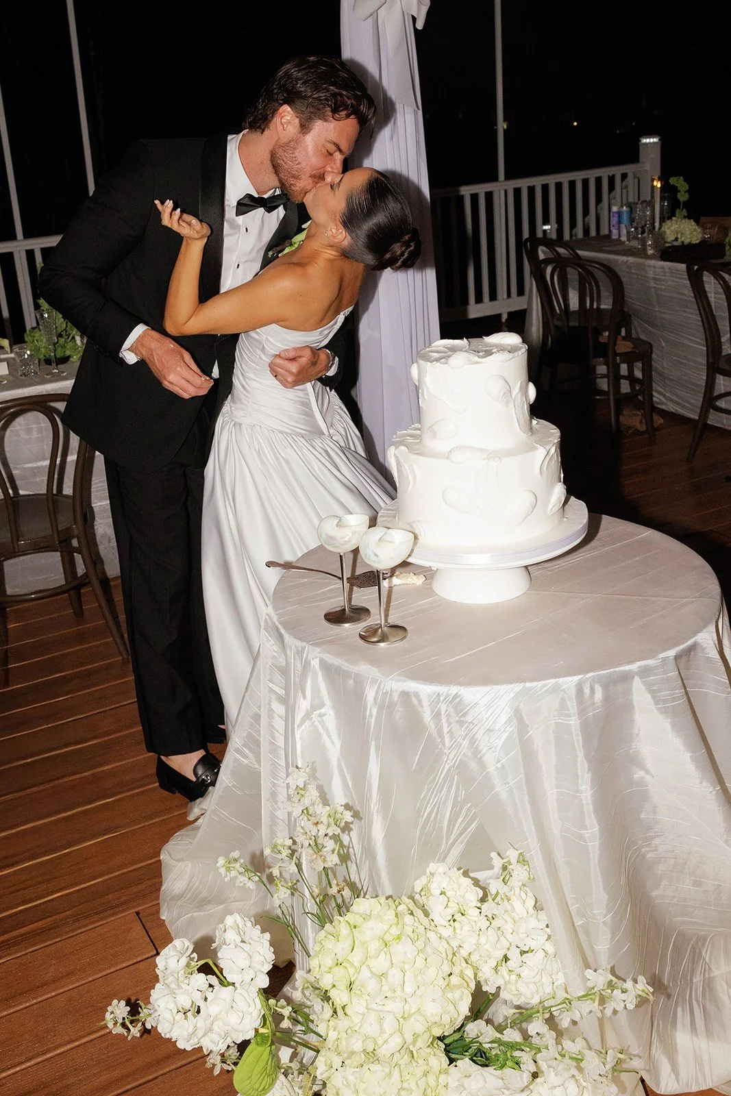 Couple kissing beside their wedding cake
