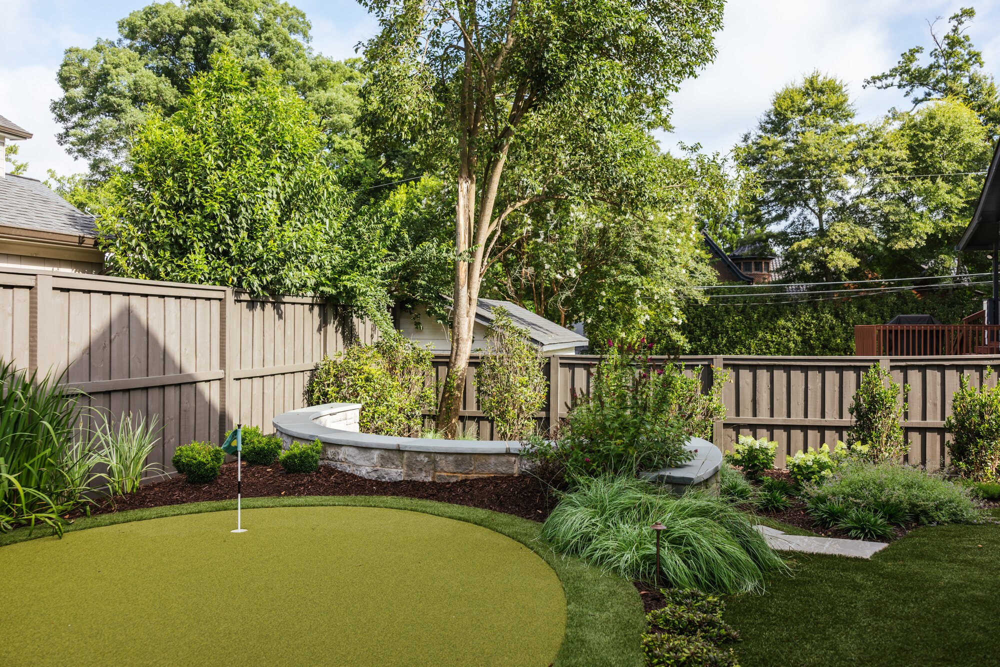 Putting green, mature tree, and curved stone terrace