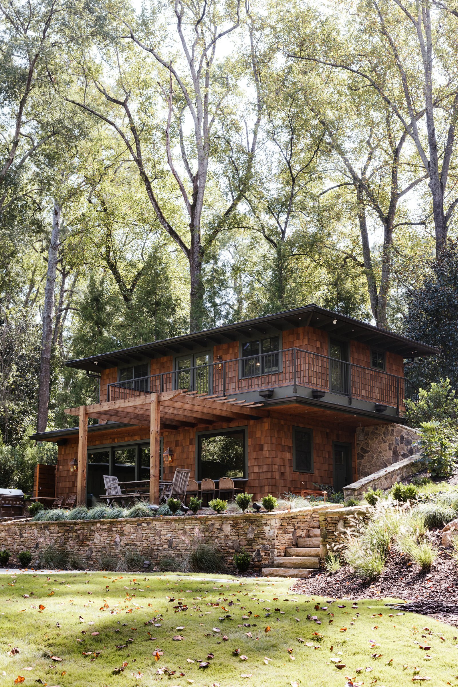 Vertical view of the cedar-shingled house beneath the woodland canopy