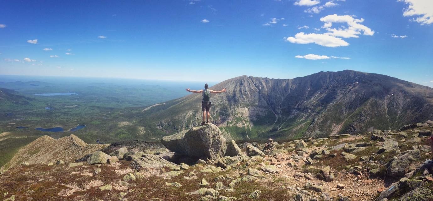 Cody standing on a boulder overlooking a mountain landscape
