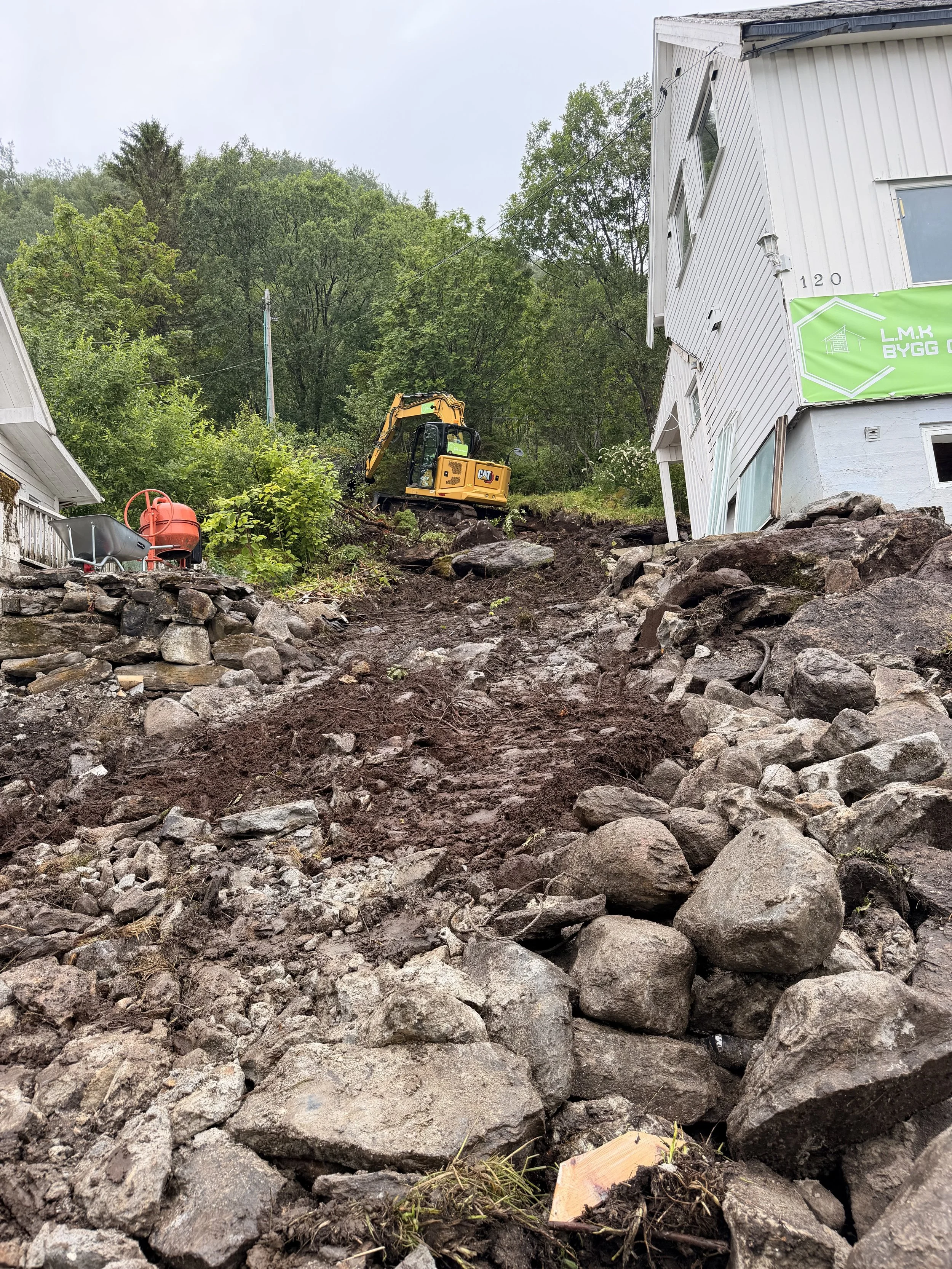 Gravemaskin under grunnarbeid ved bolig