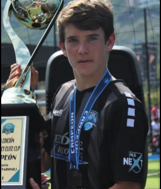 Player wearing an LSA uniform holding a championship trophy