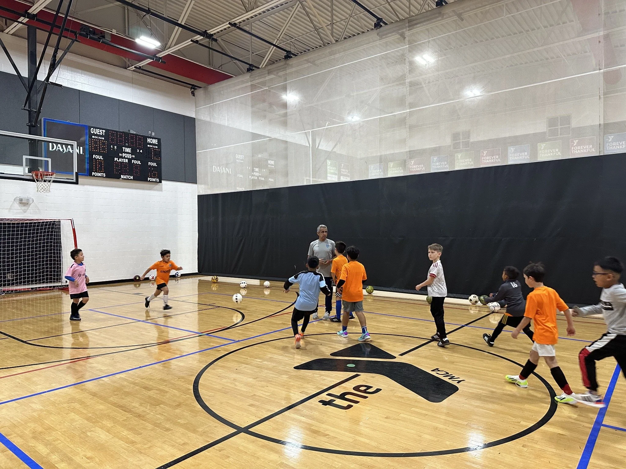 Players practicing ball control with a coach on the indoor futsal court