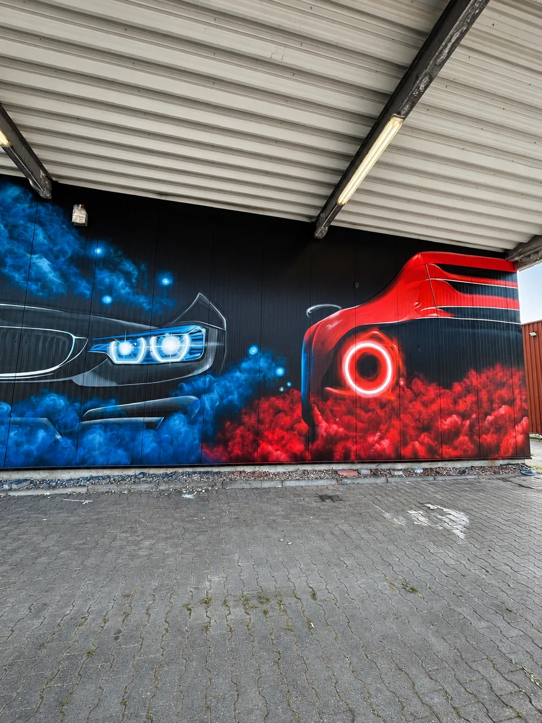 Detail der Autowerkstatt-Fassade in Erlensee mit blauer Fahrzeugfront und rotem Fahrzeugheck