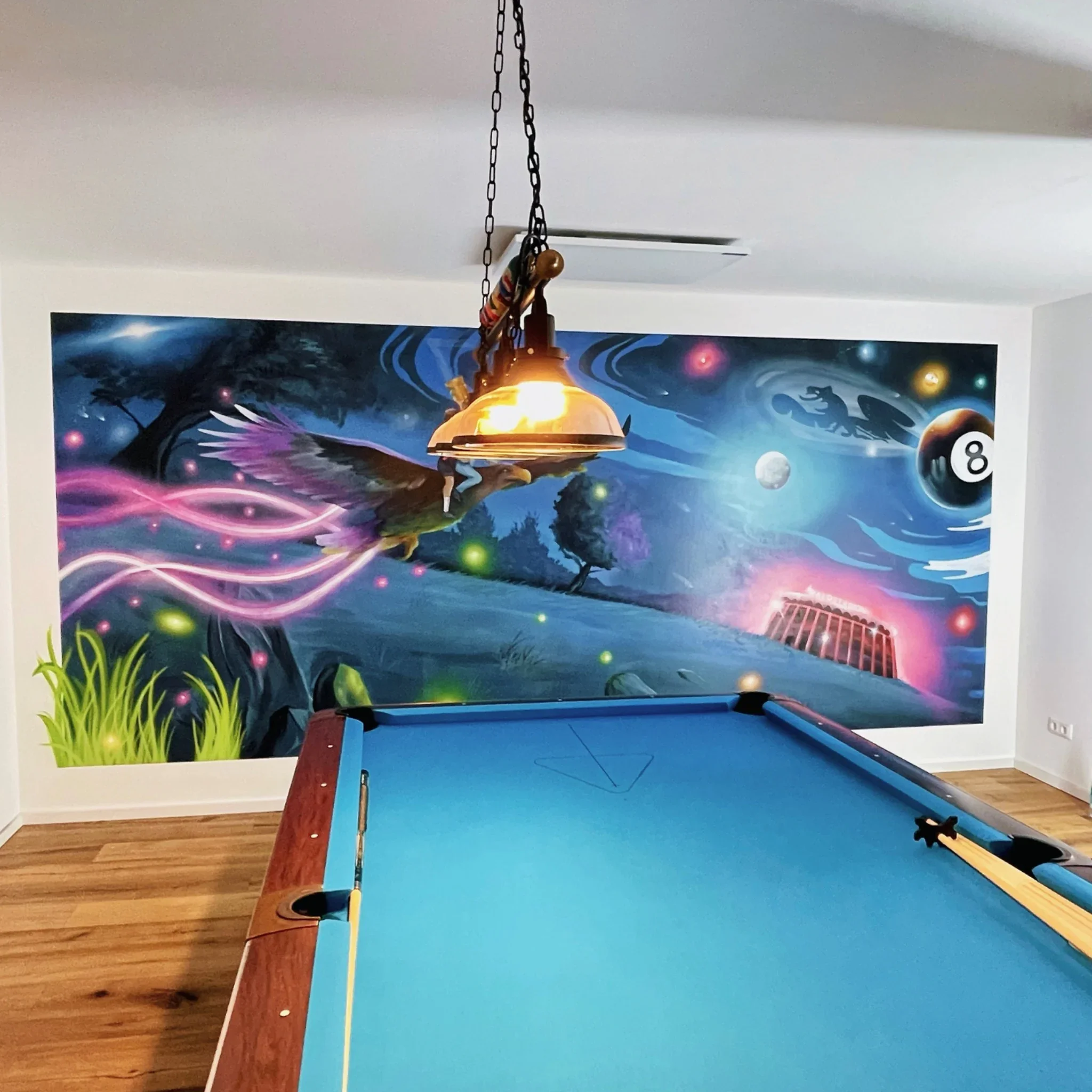 Privates Billardzimmer mit Fantasy-Wandmalerei hinter dem Billardtisch, leuchtenden Farbspuren und Billardkugeln