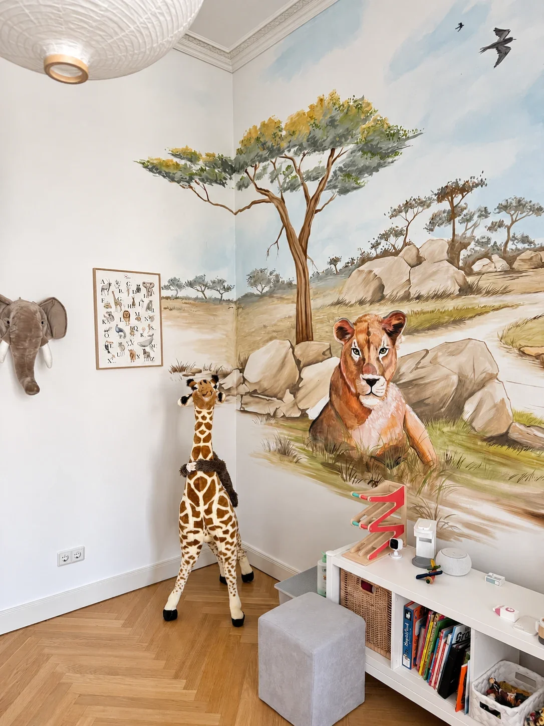 Detail des Safari-Wandbilds im Kinderzimmer in Frankfurt-Westend mit Löwe, Akazie und Felsen