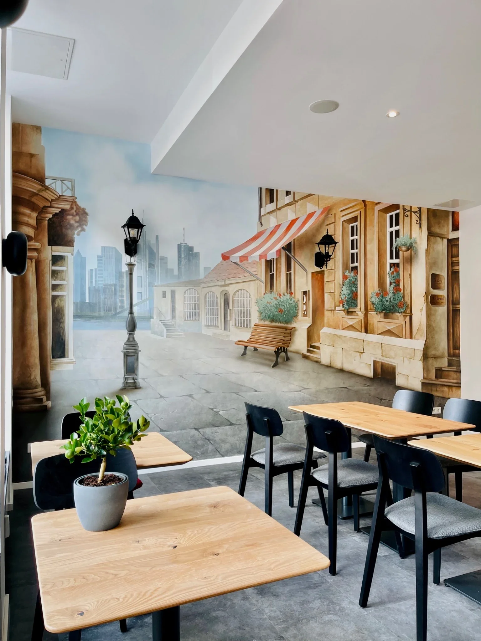 Café in Frankfurt-Sachsenhausen mit Illusionsmalerei einer Straße, Häuserfassaden und gemalten Laternen