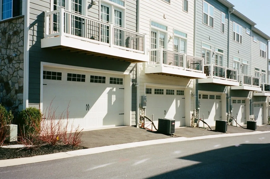 White residential garage doors beneath coastal-style balconies