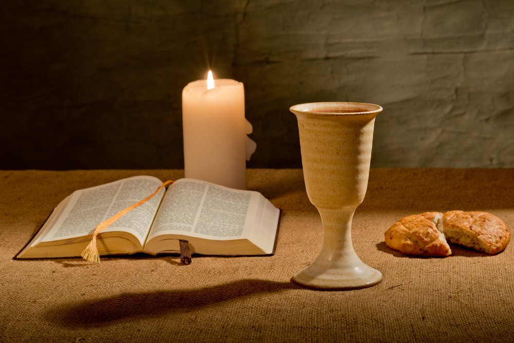 Open Bible, candle, and communion cup on a table