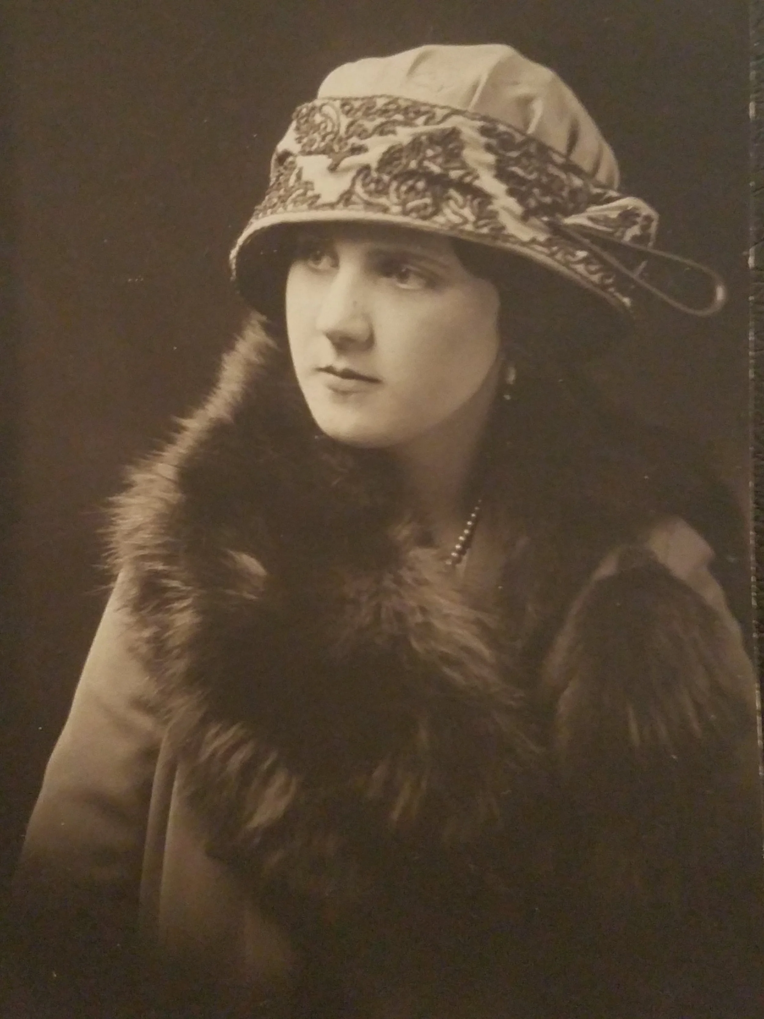 Helen Gladys Robertson Verhoek studio portrait circa 1925 in embroidered cloche hat with patterned band and dark fur wrap — the face inherited from her grandmother Margaret McKenny who died of tuberculosis in 1884