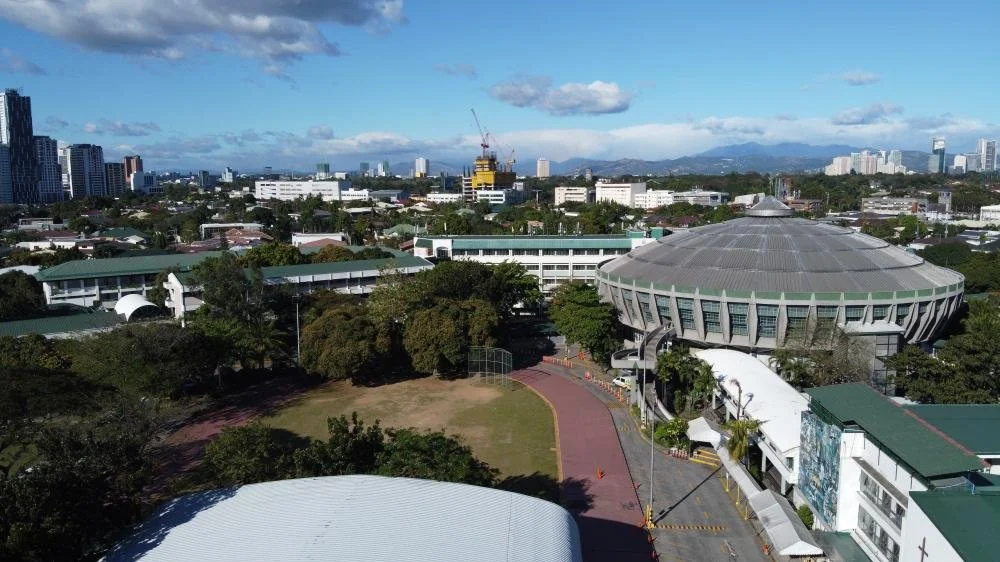 The interior of the St. Benilde dome, a vast circular hall ringed with tiered lights above a polished basketball court bearing the La Salle Green Hills star