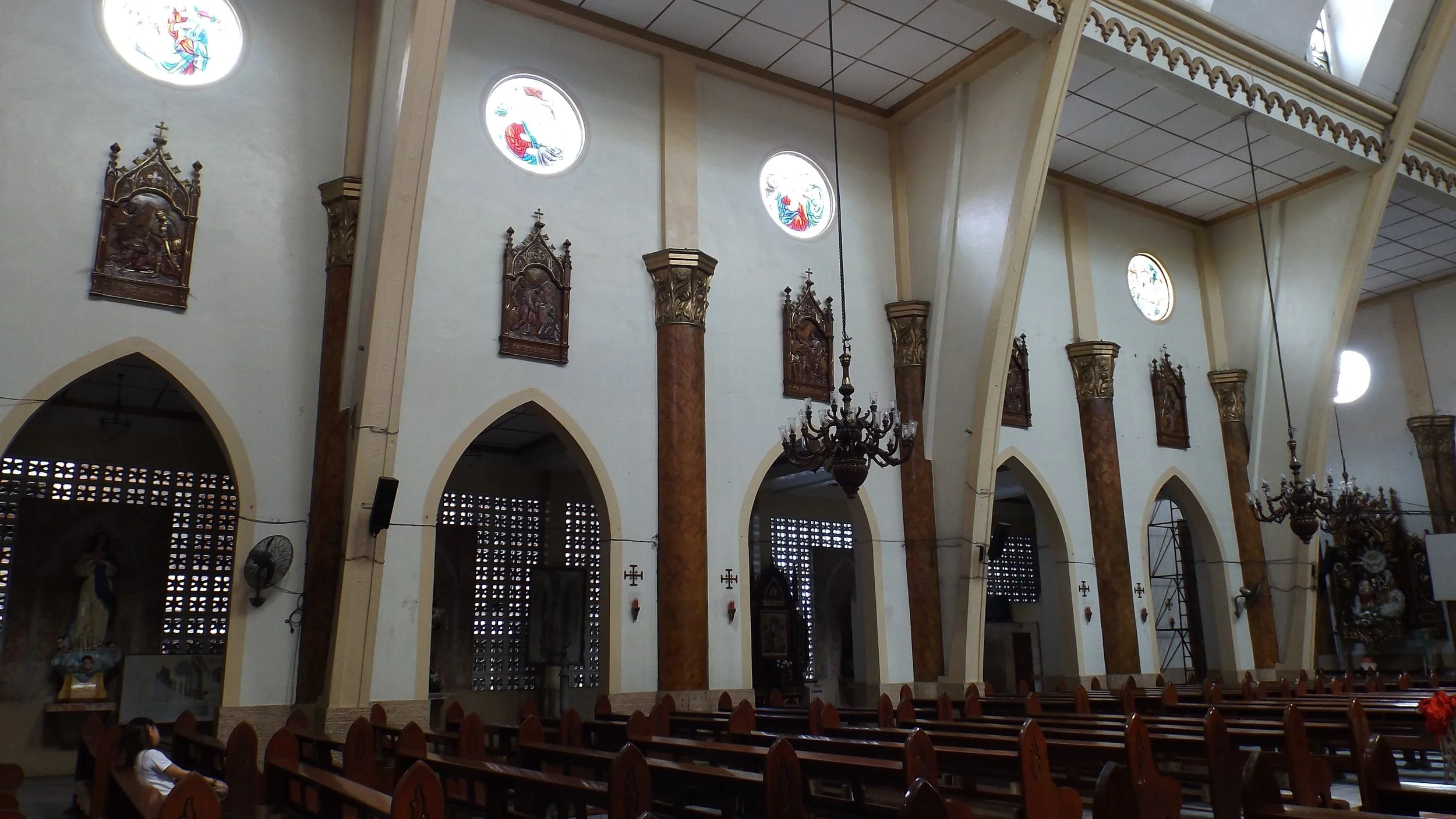Side nave of Espiritu Santo Parish showing Gothic arches, rose windows, and carved Stations of the Cross