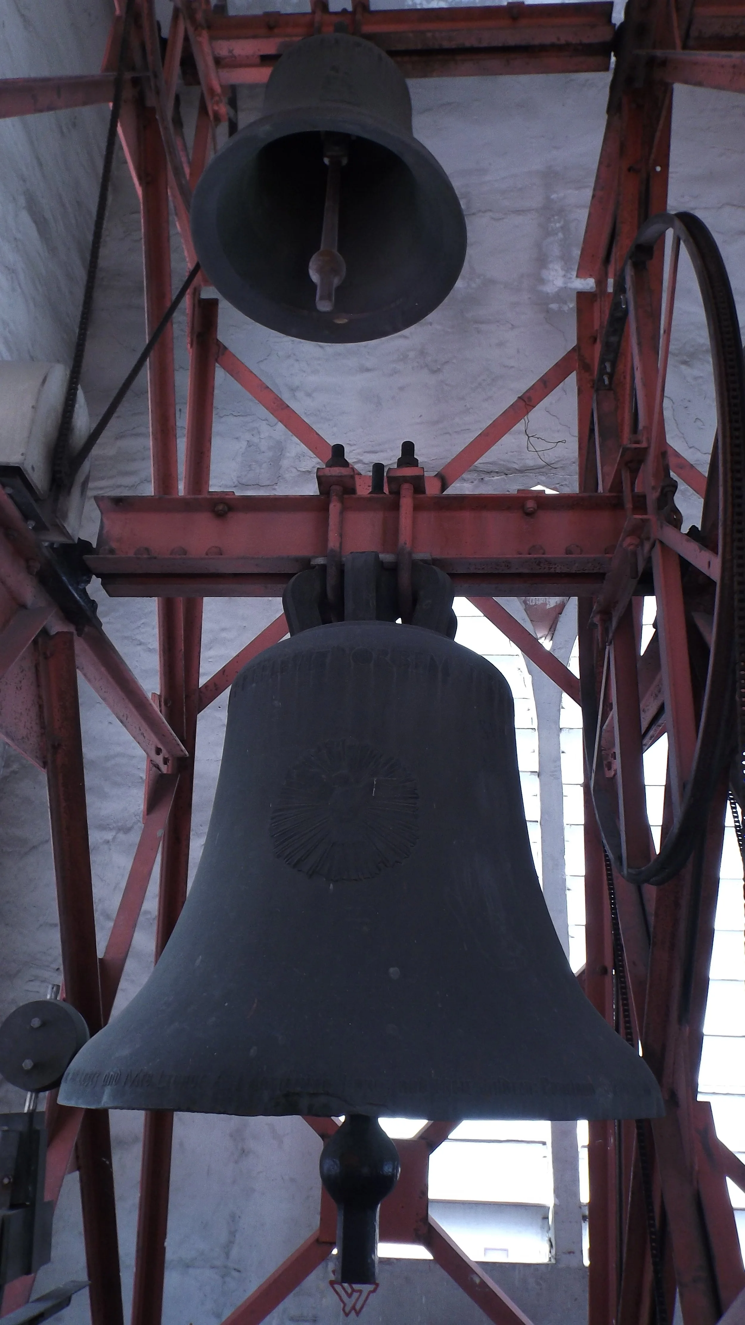 A bronze church bell in the bell tower of Espiritu Santo Parish, mounted on a red steel frame