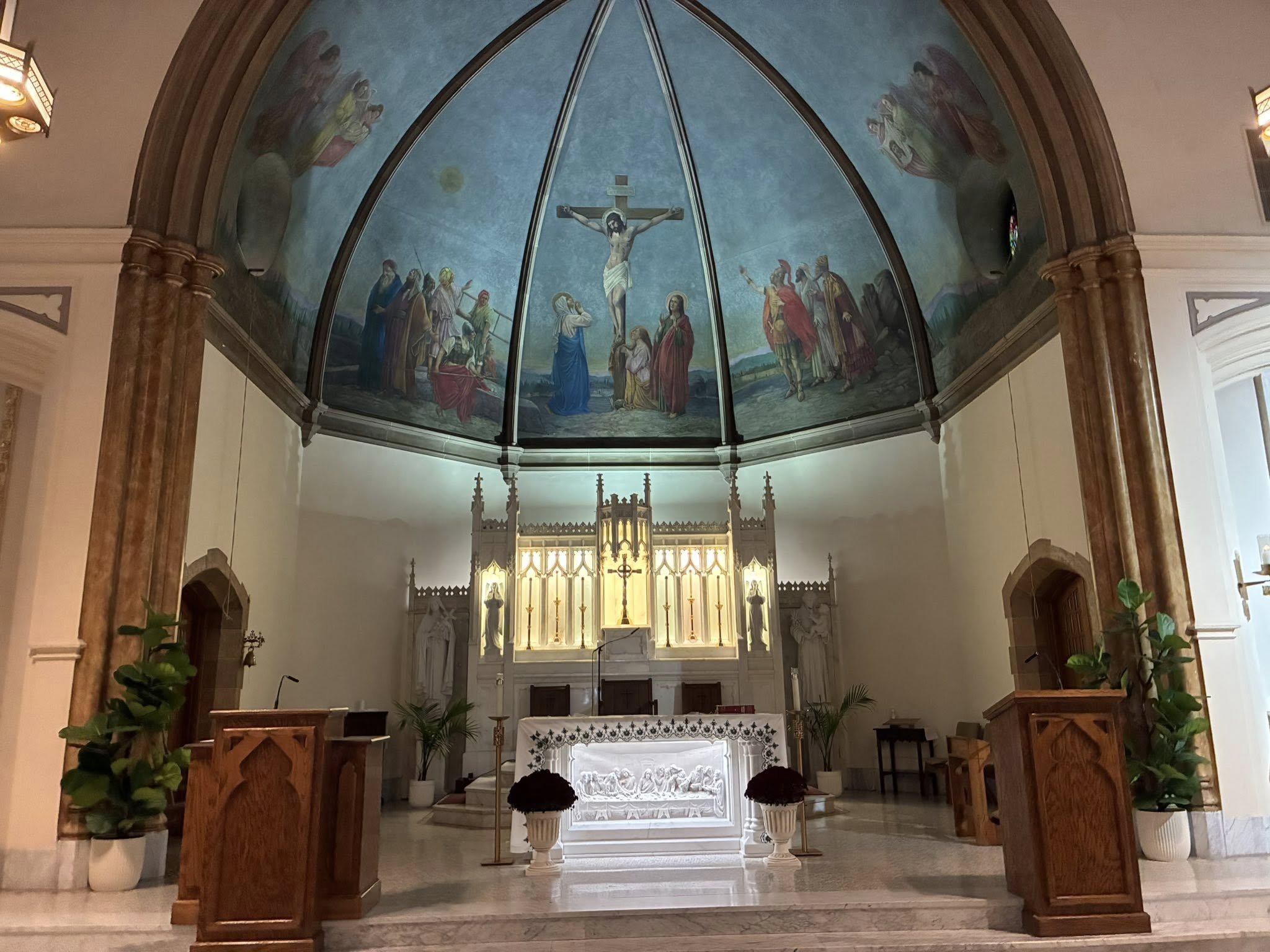Interior of St. Aloysius Church showing altar, apse mural of the Crucifixion, and Gothic architecture