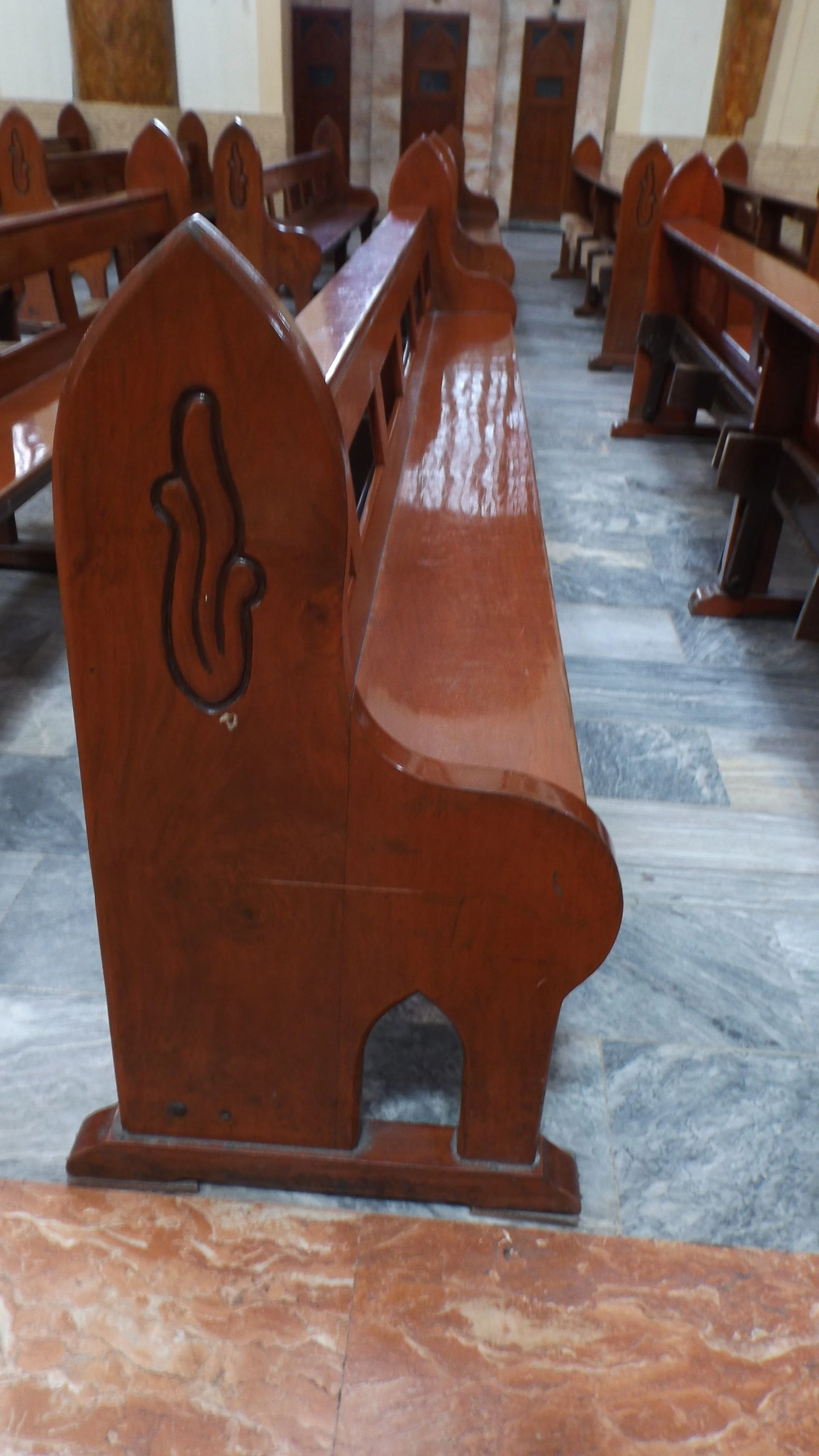 A polished wooden Gothic-arched pew inside Espiritu Santo Parish