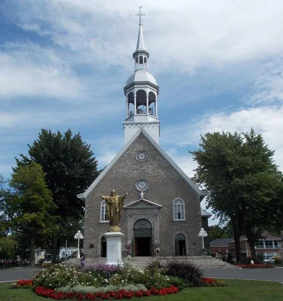 Sainte-Famille Church exterior, Boucherville, with golden statue and flower gardens