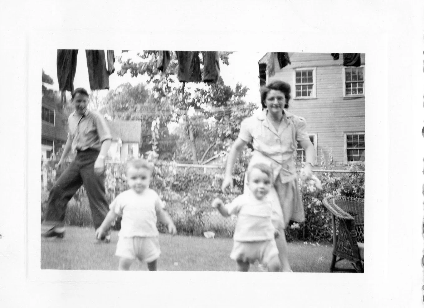 A mother chases her twin toddler sons across a summer backyard, circa 1947, Caldwell, New Jersey