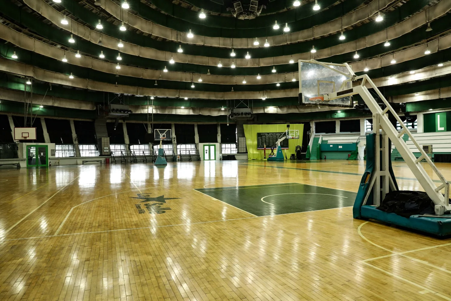 The domed St. Benilde Gymnasium at La Salle Green Hills, a circular concrete structure topped with a star, seen across the school field