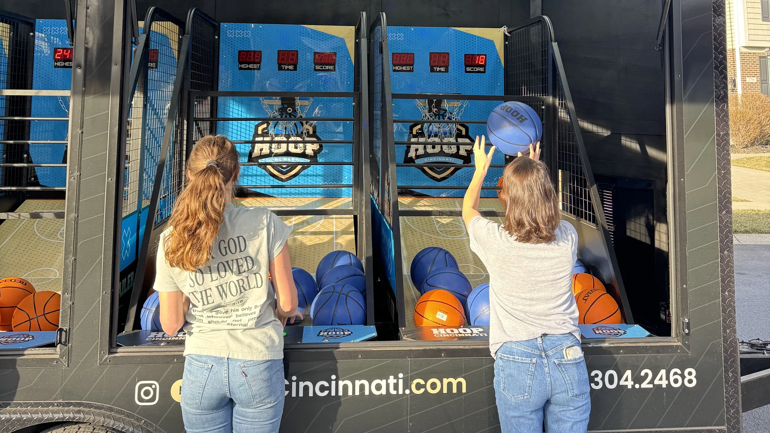 Two women playing basketball arcade in neighborhood