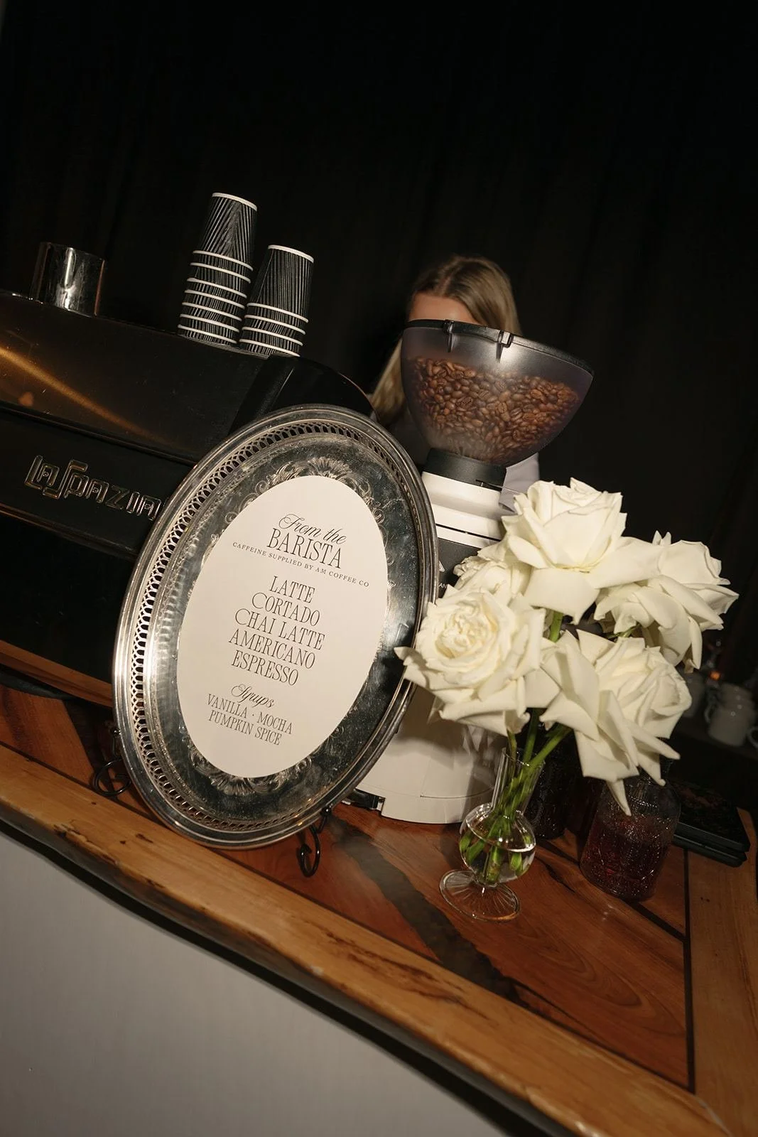 AM Coffee Co espresso bar menu on a silver tray beside white roses and the grinder