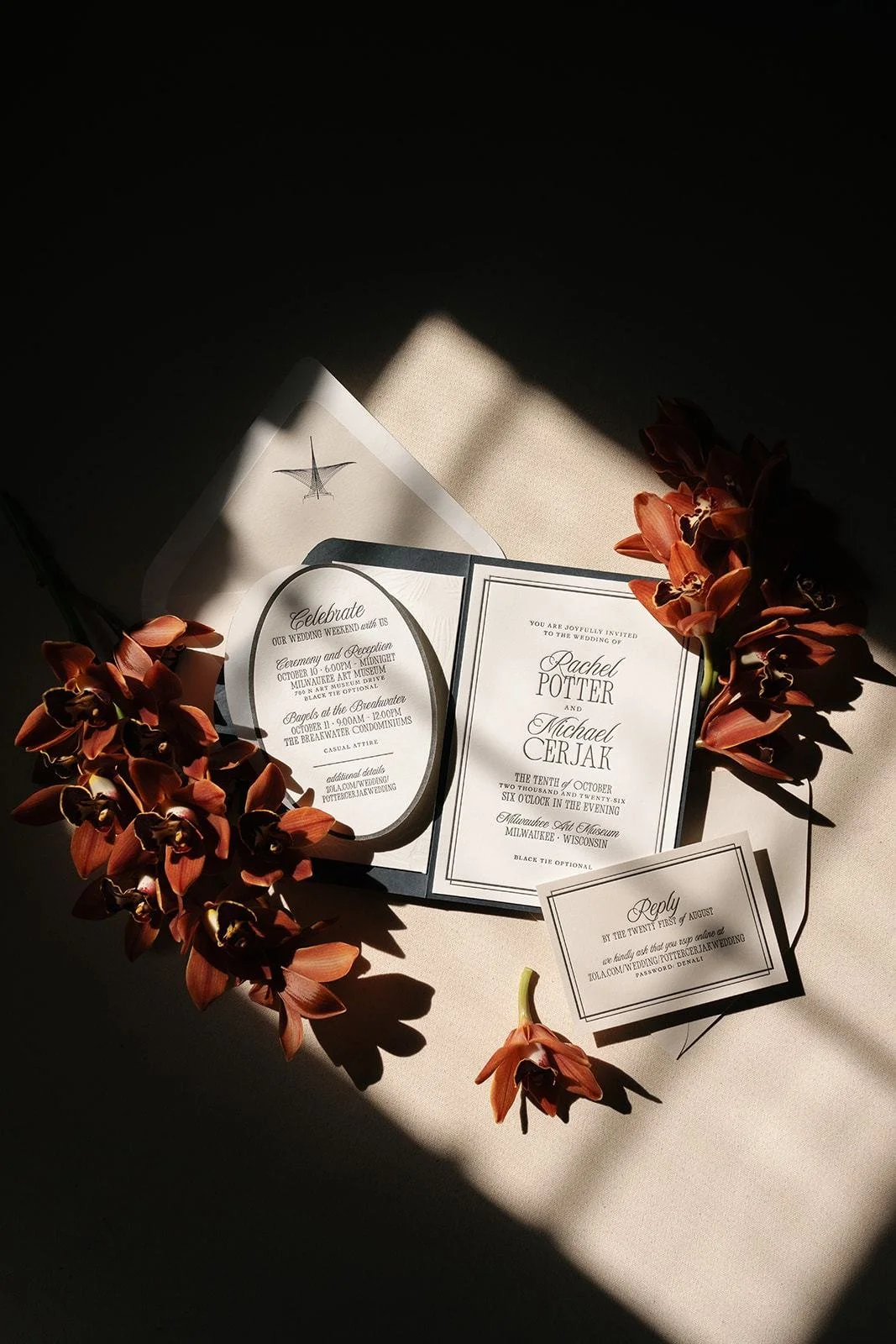 Wedding invitation suite with deep red orchids in raking light